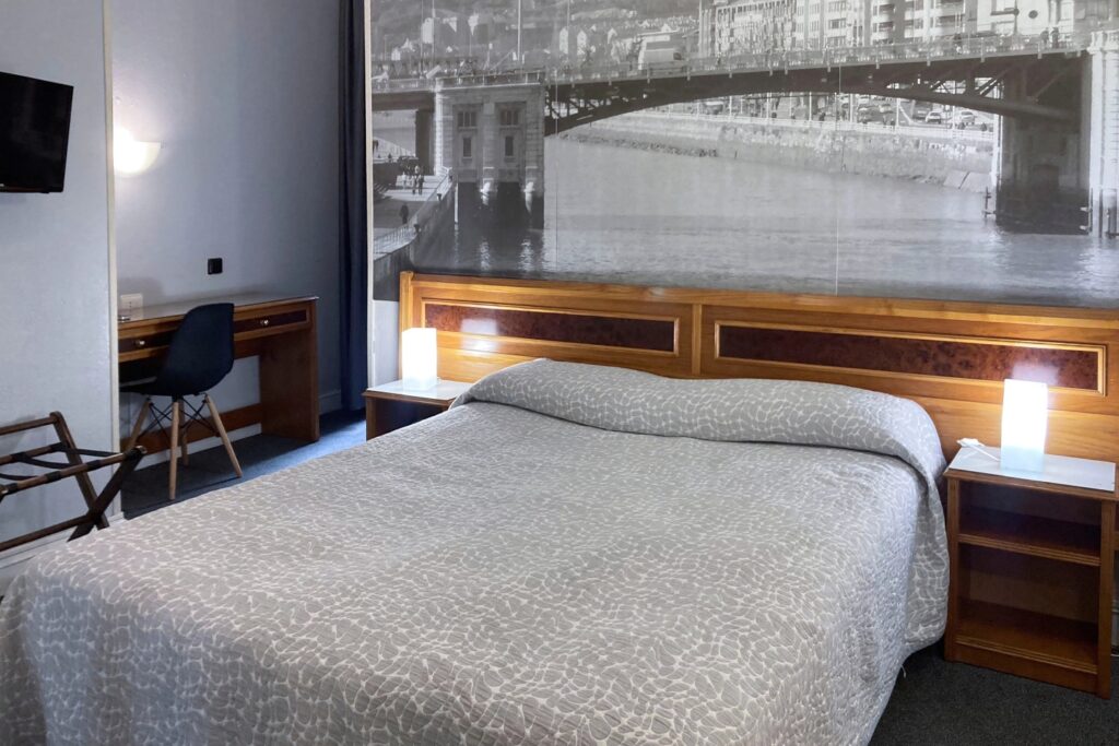 Habitación doble matrimonial del Hotel Photo Zabalburu con cama grande, escritorio y decoración urbana