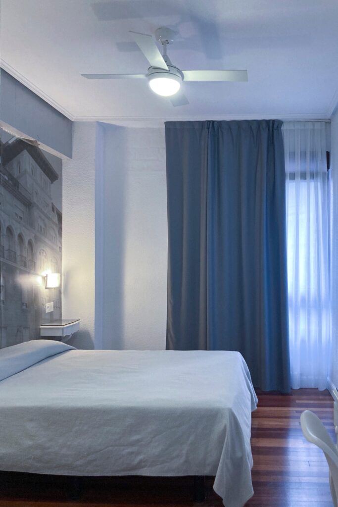 Habitación doble matrimonial del Hotel Photo Zabalburu con cama grande, suelo de madera y ventilador de techo